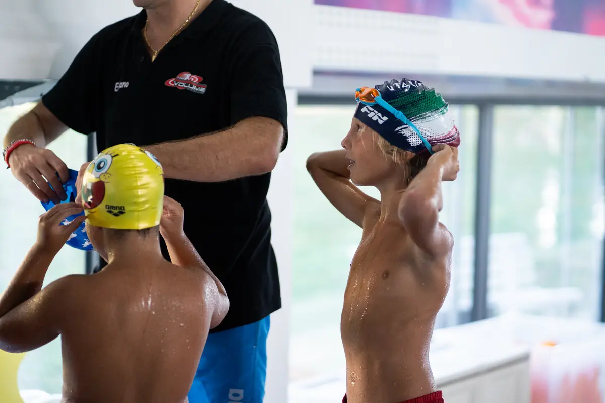 Istruttore con due bambini a bordo vasca durante il corso di nuoto